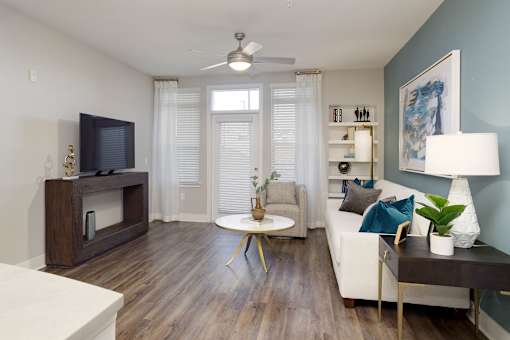 A living room with a television, a couch, a table, and a plant.