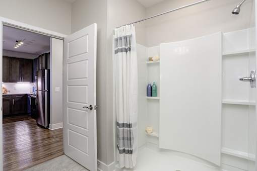 A white bathroom with a shower curtain and a white door.