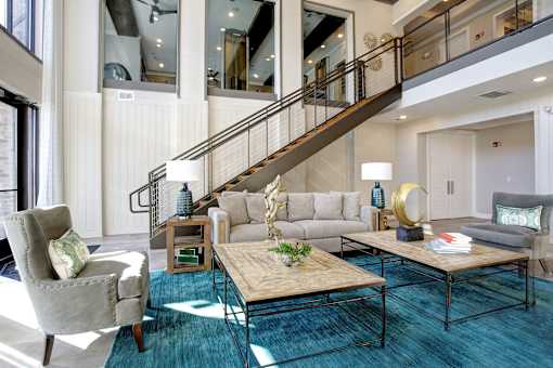 A living room with a staircase and a grey couch.