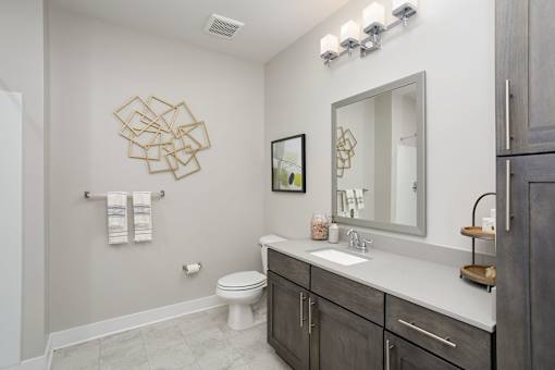 A bathroom with a toilet, sink, and a mirror.