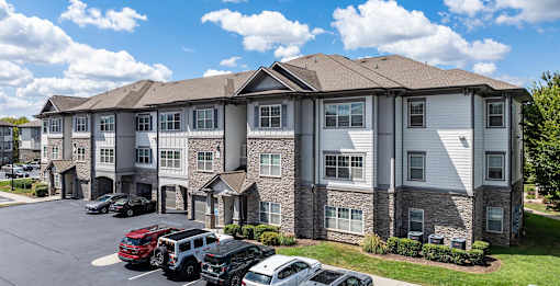 an apartment building with cars parked in a parking lot