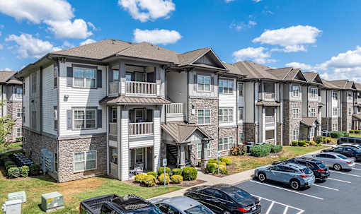 an apartment building with cars parked in a parking lot