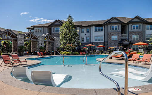 a swimming pool with chairs and a building in the background