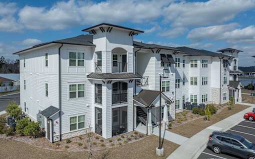 Pet-Friendly Apartments in Brunswick, GA - Vintage Brunswick - Property Exterior with White Walls, Manicured Plant Beds, and View of Parking Area
