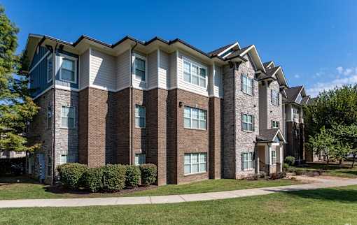 a brick apartment building with a sidewalk in front of it