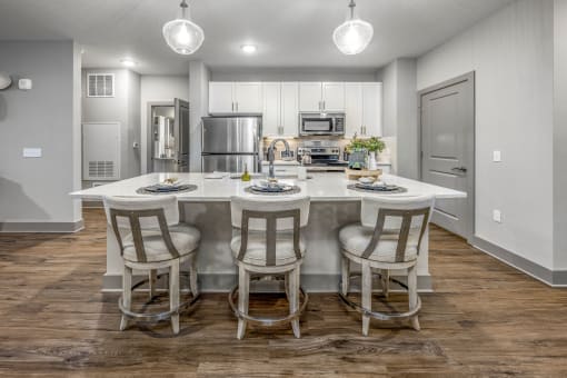 an open kitchen with a large island with chairs around it