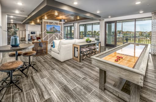 A game room with a shuffle board and seating