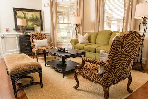 A zebra print chair sits in a living room with a green couch and a coffee table.
