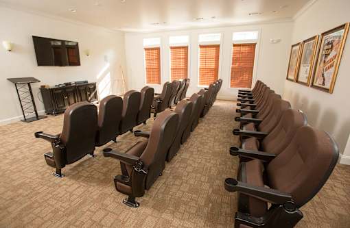 A room with rows of brown chairs and a television on the wall.