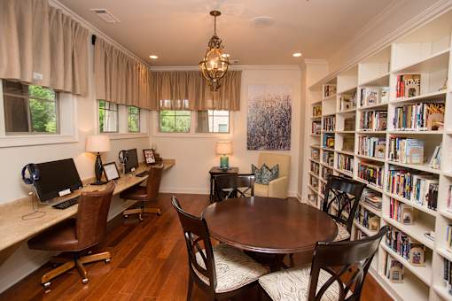 A room with a desk, chairs, and a bookshelf filled with books.