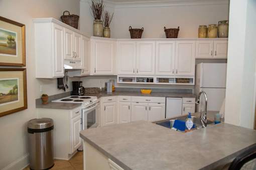 A kitchen with white cabinets and a marble countertop.