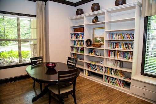 A room with a table, chairs and a bookshelf.