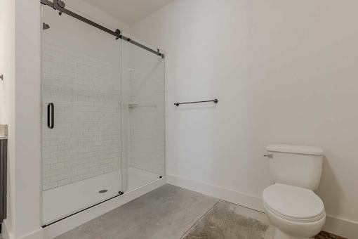 A white toilet sits next to a walk-in shower with a glass door.