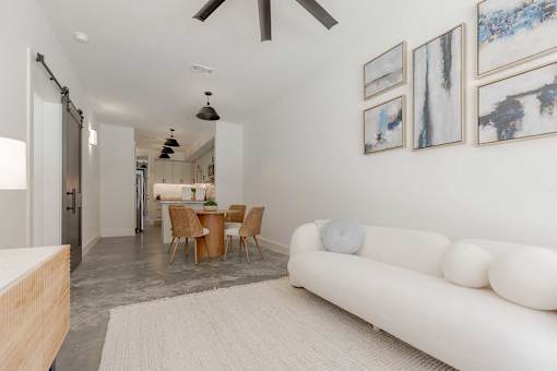A white couch sits in a room with a table and chairs.