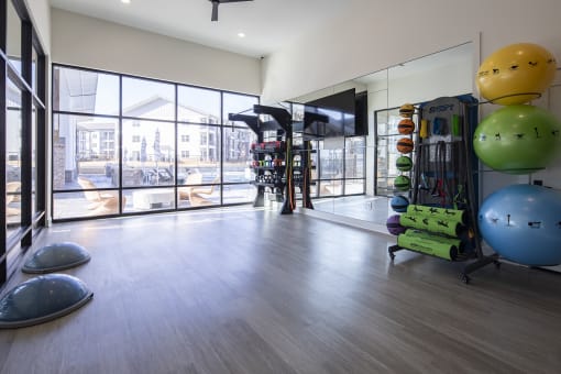 a fitness room with weights and balls and a large window