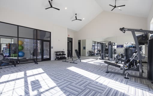 a gym with weights and other equipment in a building with windows