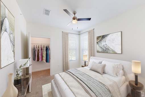 A bedroom with a large bed, a ceiling fan, and a closet with clothes hanging.