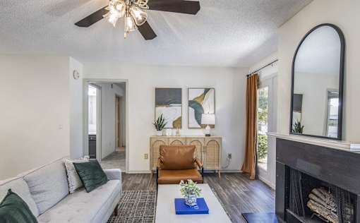 A living room with a grey couch, a fireplace, and a ceiling fan.