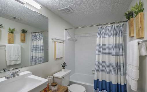 A bathroom with a white sink, toilet, and a blue and white striped shower curtain.