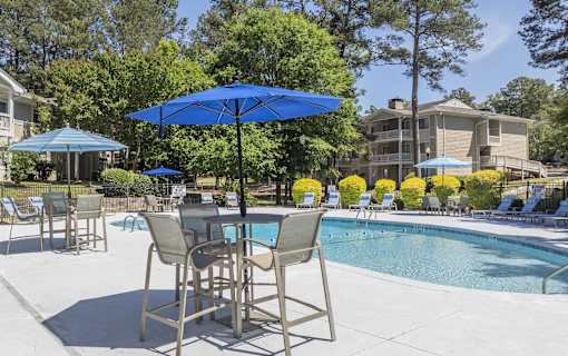A blue umbrella is in front of a pool.