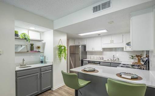 A kitchen with a white countertop and green chairs.