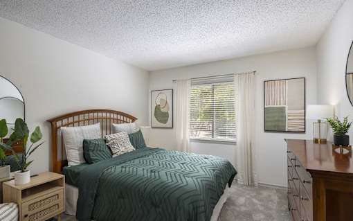 A bedroom with a bed, nightstand, and window.