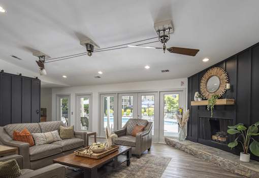 A living room with a grey couch, a wooden coffee table, and a fireplace with a mirror above it.
