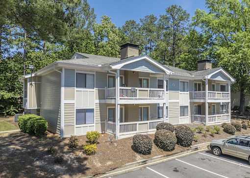 A two-story apartment building with a car parked in front.
