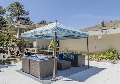 A patio with a blue canopy and a white fence.
