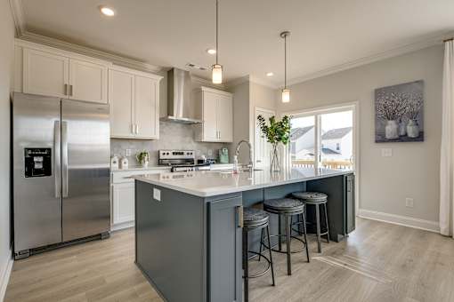 A kitchen with a refrigerator, stove, and bar stools.