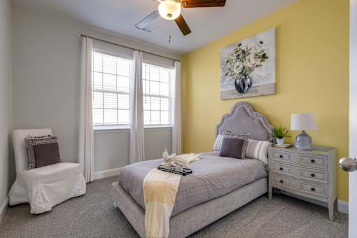 A bedroom with a bed, chair, and window.
