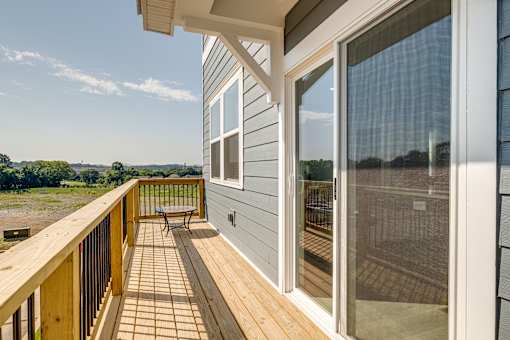A balcony with a bench and a view of the sky.