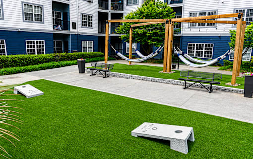 A hammock is suspended between two wooden posts in a grassy courtyard.