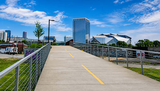 A walkway with a metal railing leads to a city skyline.