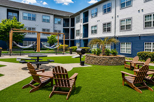 A sunny day at a residential complex with a hammock, picnic table, and chairs.
