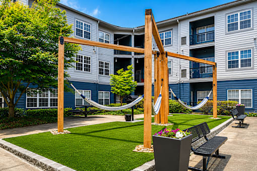A playground with a slide and a hammock in front of apartment buildings.