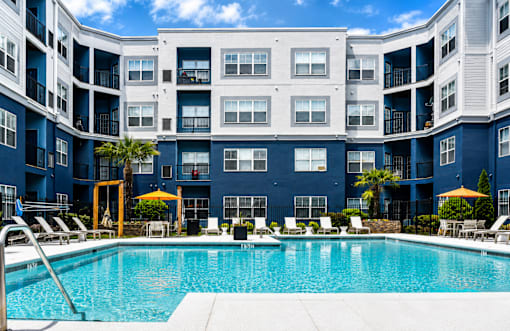 A large swimming pool in front of a blue building with white balconies.