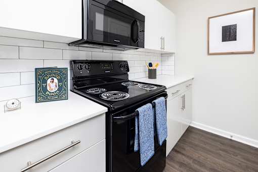 A black stove top oven with blue towels hanging on it.
