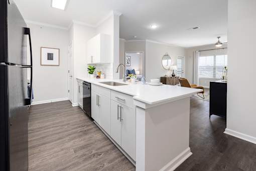 A modern kitchen with white cabinets and a black refrigerator.
