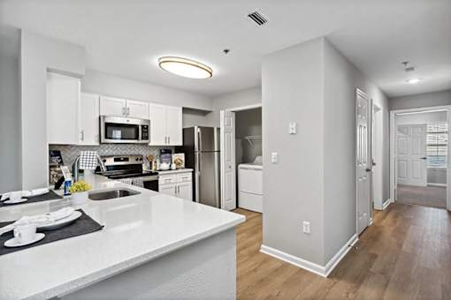 A modern kitchen with white countertops and stainless steel appliances.