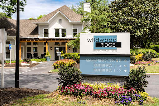 A sign for Wildwood Ridge Premier Apartment Homes is in front of a building.