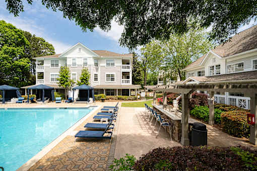 A pool area with sun loungers and a building in the background.