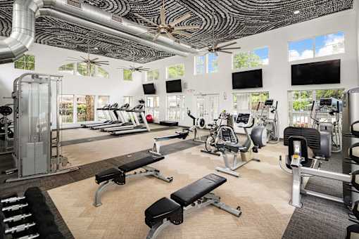 A gym with a variety of equipment including treadmills, weights, and exercise machines.