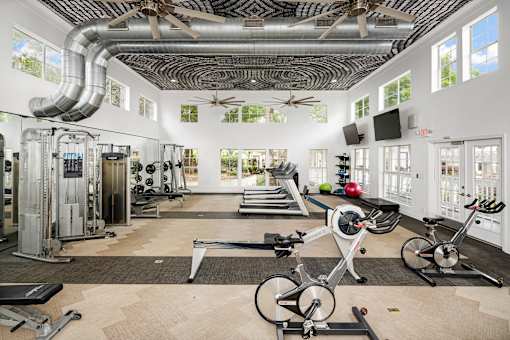 A gym with a variety of equipment including treadmills, weights, and exercise bikes.