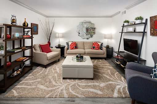 A living room with a beige sofa, a grey armchair, a coffee table, and a television.