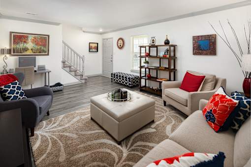A living room with a rug, a couch, a chair, a coffee table, and a staircase.