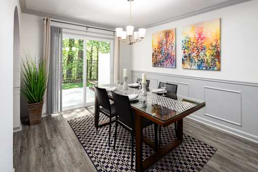 A dining room with a table set for two and a painting on the wall.