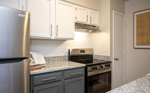 A kitchen with a refrigerator, oven, and cabinets.