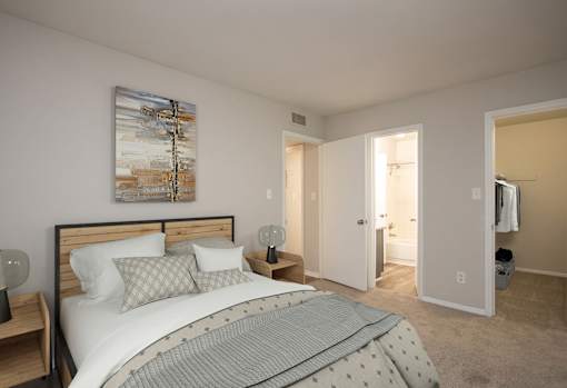 A bedroom with a bed, nightstands, and a painting on the wall.