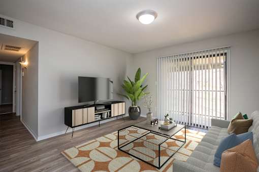 A living room with a television, a plant, and a couch.